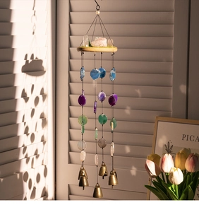 Detail of agate wind chime with brass bells and crystal stones by a sunlit window