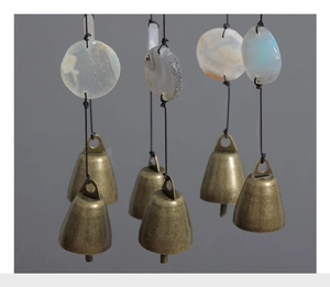 Detail of vintage agate slices with brass bells hanging on black ropes for balcony decor