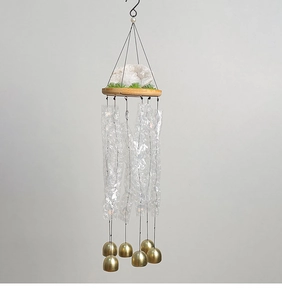 Détail de carillon avec cristal blanc, base en bois et six cloches en métal doré mat