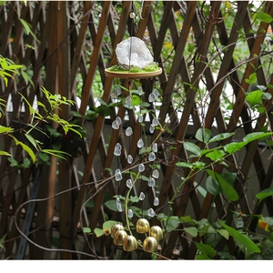 Détail du carillon en cristal avec pierres brutes, mousse et cloches en laiton au jardin