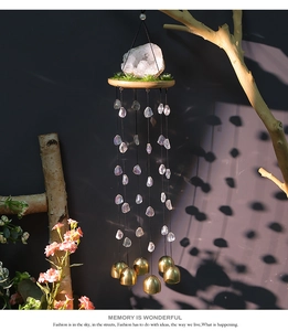 Vue détaillée d'un carillon en cristal avec cloches en laiton sur une branche