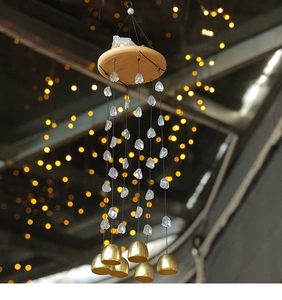 Détail d'un carillon en cristal naturel avec plateau en bois et cloches dorées