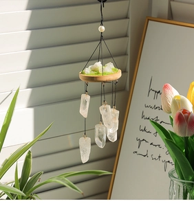Detail view of natural white crystal wind chime with wooden base and mossy stone texture
