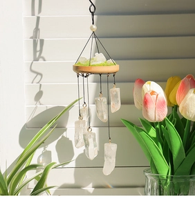 Close-up of natural clear quartz crystal wind chime with wood base and moss detail