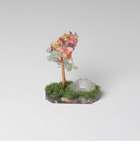 Close-up of handmade crystal tree with colorful stones and natural moss on a white base
