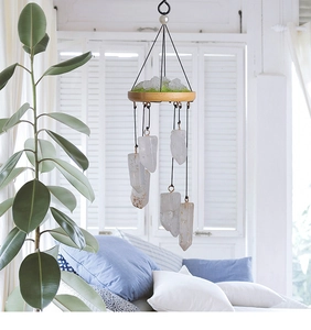 Detail of natural white crystal prism wind chime with wooden base and green moss decor