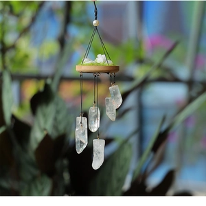 Detail of natural white crystal prism wind chime with moss-covered wooden base