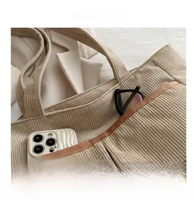 Close-up of beige corduroy tote bag featuring a practical outer pocket with brown trim