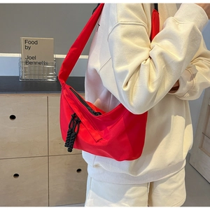 Détail du sac bandoulière rouge en nylon avec tirette de fermeture en corde