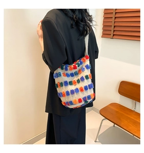 Detail of colorful tufted shoulder bag on white plush base with vibrant orange and blue balls