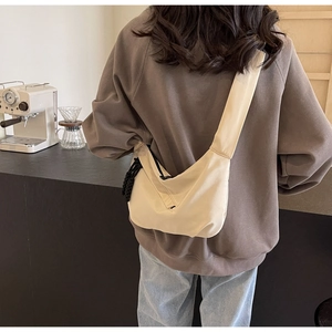 Detail of the durable beige nylon fabric texture and woven zipper pull on a half-moon bag
