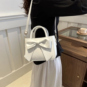 Borsa bianca minimalista con fiocco, manico e tracolla indossata da una modella