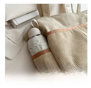 Detail of beige corduroy tote bag side pocket with umbrella and brown webbing trim