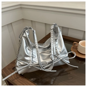 Close-up of metallic silver tote bag featuring pleated texture and bow details