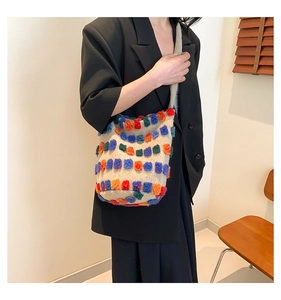 Detail of white textured bucket bag with vibrant colorful 3D plush dots and wide strap