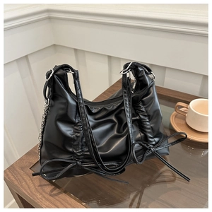 Detail of black pleated tote bag with bow decoration and silver metal chain strap