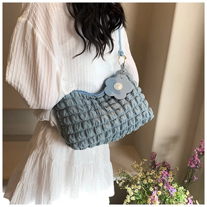 Blue bubble textured cloud bag with floral charm shown on model in home setting