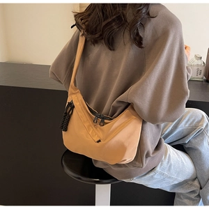 Détail du sac demi-lune en nylon camel avec fermetures noires et breloque en corde tressée