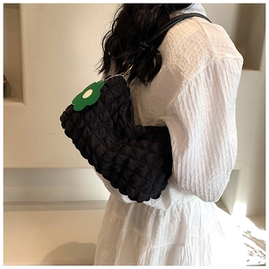 Detail of black popcorn texture shoulder bag with green floral charm accent