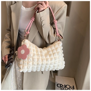 Detail of white bubble texture shoulder bag with pink ribbon strap and floral charm