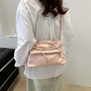 Pink crossbody bag with decorative bow and fashion text shown in lifestyle setting