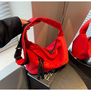 Détail du grand sac bandoulière rouge avec boucle noire et tirettes de fermeture