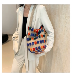 Détail de carrés touffetés colorés sur un sac cabas en tricot crème à bandoulière