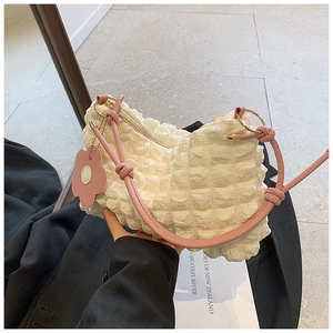 Detail of white popcorn textured tote bag with pink shoulder strap and flower charm