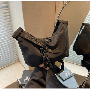 Sac bandoulière demi-lune noir minimaliste avec tirettes tissées sur table en bois