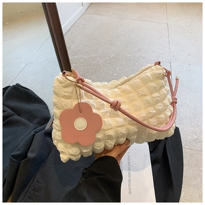 Detail of cream bubble texture handbag with pink leather handle and floral charm