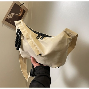 Détail du sac bandoulière demi-lune blanc cassé avec double zip et gland tressé noir