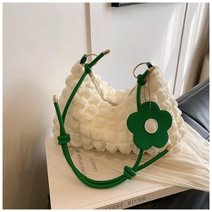 Detail of white bubble textured tote bag with green handles and floral charm accessory