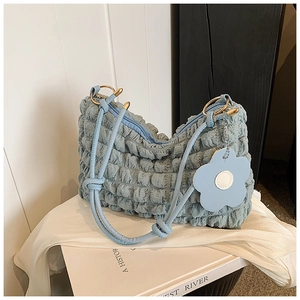 Detailed close-up of light blue pleated tote bag texture with flower charm and knot strap
