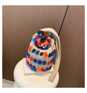 Detail of plush cream bucket bag with colorful pom-poms and matching faux fur strap