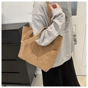 Detail einer braunen Cord-Tragetasche mit funktionalen Fronttaschen und einem Vintage-Look