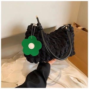 Detail of black bubble textured handbag featuring a vibrant green flower charm