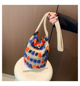 Détail d'un sac seau en tricot créatif avec pompons colorés et poignée souple