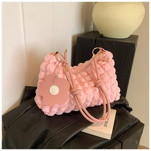 Detailed macro shot of pink bubble texture fabric and flower charm on the chic cloud bag