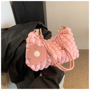 Close-up of pink bubble textured handbag with floral charm and metallic gold hardware