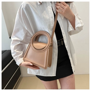 Minimalist beige geometric handbag with circular handle and crossbody strap detail