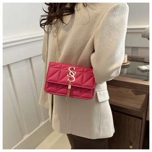 Gros plan d'un sac matelassé rose vif avec logo doré et pompon sur un modèle