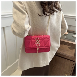 Détail du sac matelassé rose avec logo à pompon doré et bandoulière chaîne sur modèle