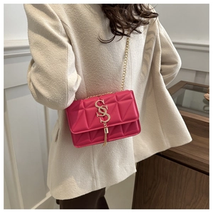 Détail du sac matelassé rose avec logo SS doré et pompon sur un manteau beige