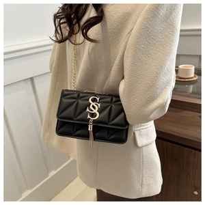 Détail du sac bandoulière matelassé noir avec boucle dorée en S et pompon luxueux