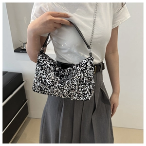 Detailed view of women's sequin crossbody bag with chain strap worn by a model