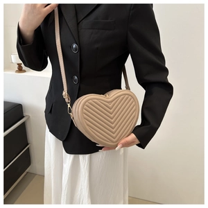 Detailed close-up of a beige heart-shaped quilted crossbody bag with elegant V-stitching