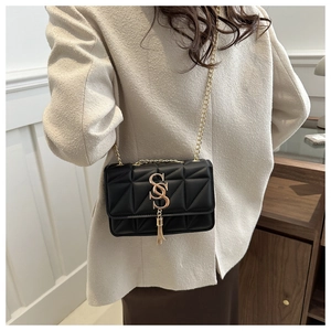 Détail du sac matelassé noir avec logo double S doré et pompon métallique élégant