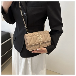 Détail d'un sac à bandoulière matelassé beige avec chaîne dorée et pompons métalliques