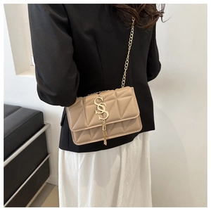 Détails du sac matelassé beige avec bandoulière chaîne dorée et pompon métallique chic