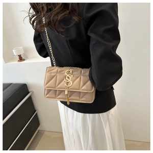 Détail du sac matelassé beige avec bandoulière chaîne dorée et breloque à pompon
